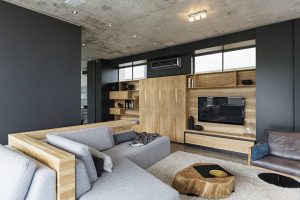 Salon en bois avec canapé gris et murs gris foncé